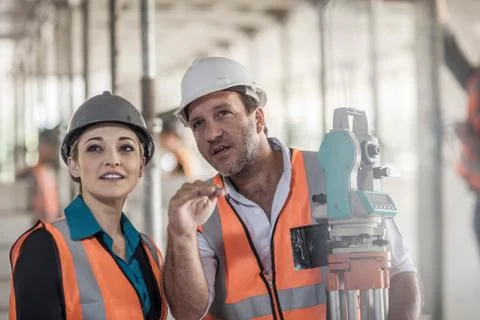 Surveyor explaining to female builder on construction site Stock Photos