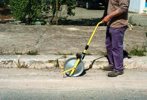 Surveyor with measuring wheel (odometer) detects the length of an excavation Stock Photos