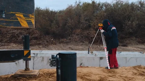 A surveyor using a theodolite an industrial construction. Stock Footage 321003499