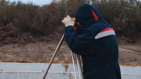 A surveyor using a theodolite at an industrial construction site. Stock Footage 321003671