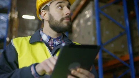 Surveyor Wearing Hard Hat Holds Tablet and Counts Merchandise in Warehouse. Stock Footage