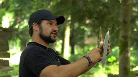 Survival instructor demonstrating knife throwing technique during bushcraft Stock Footage 330970581