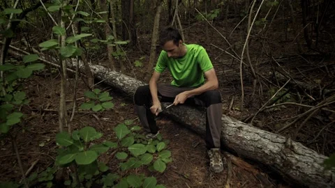 Survivalist in the forest sharpens a stick with a knife Stock Footage 161485003