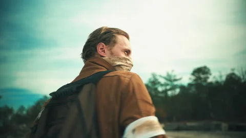 Survivor Puts On Backpack And Takes In His Surrounding Stock Footage 154609408