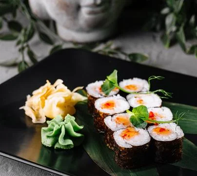 Sushi array garnished with wasabi and ginger on a stylish black plate, ador.. Stock Photos