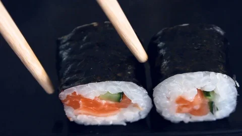 Sushi on the black table. Chopsticks take sushi closeup. Man eats sushi. Lunc Stock Footage 120996393