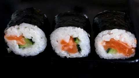 Sushi on the black table. Chopsticks take sushi closeup. Man eats sushi. Lunc Stock Footage 121791398