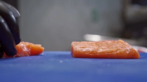 The sushi chef carefully cuts the red fish into pieces to create preforms for 스톡 동영상 150417838