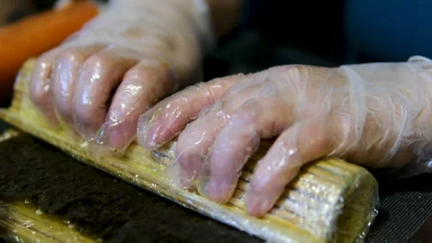 Sushi chef rolling rolls using a special bamboo mat with hands in white gloves Stock Footage 302823116