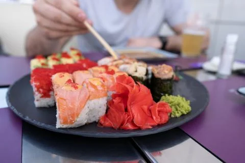Sushi closeup. The guy eats sushi and rolls with chopsticks Stock Photos