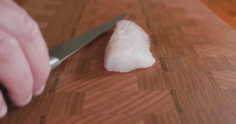 Sushi cuts thin slices of white fleshy snapper with a very sharp knife Video stock 115528420