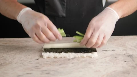 A sushi filling is applied to a bamboo mat. rice is shaped to make sushi. Asian Stock Footage 171984990