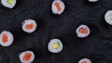 Sushi maki rolls on rotating black background top view ,fashion food background Stock Footage 220149791