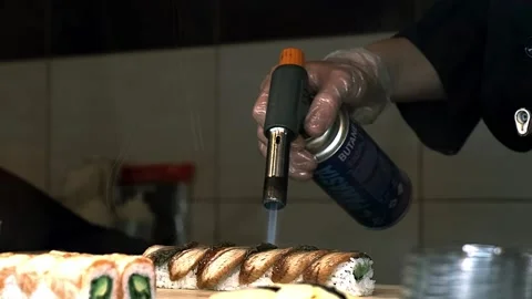 Sushi master burns fish rolls with a gas burner Stock Footage 229201075