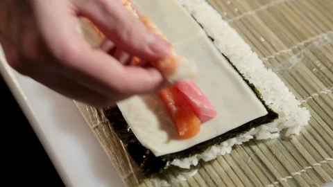 Sushi-master prepares rolls in a restaurant, puts shrimps on salmon and cheese. 스톡 동영상 87012325