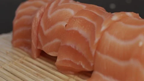 The sushi master puts cut fish slices on rice rolls. Black wood background Video stock 145343348