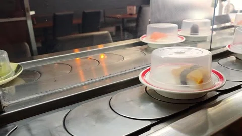 Sushi plates glide along a conveyor belt inside a Japanese restaurant, colo.. Video stock 339640234