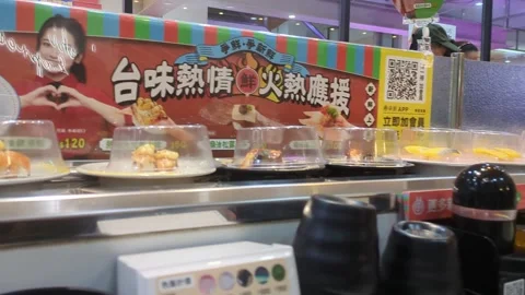 Sushi plates placed on a rotating conveyor belt inside restaurant Stock Footage 327769996