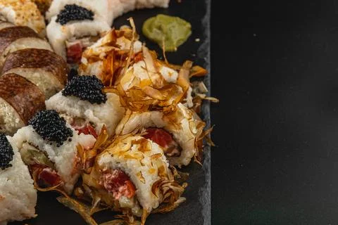 Sushi platter featuring assorted rolls and toppings served on black stone Stock Photos