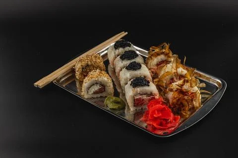 Sushi platter featuring assorted rolls with garnishes and chopsticks Stock Photos