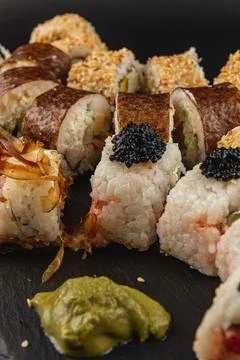 Sushi platter featuring various rolls with wasabi and caviar on black slate Stock Photos