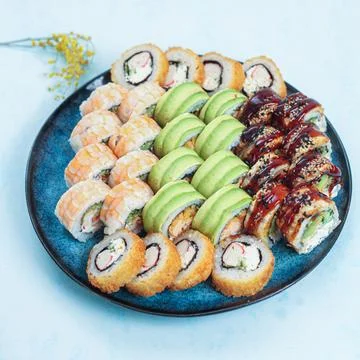 Sushi platter with various types and styles of rolls on a blue plate 库存照片