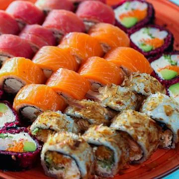 Sushi platter with various types of rolls and fish served on plate Фото