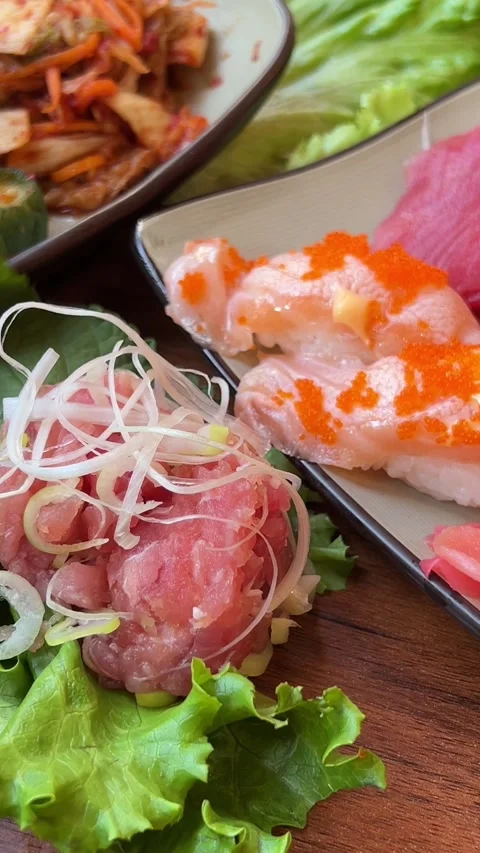 Sushi platter with vibrant rolls, sashimi, and garnishes on a wooden table in a Stock Footage 322097319