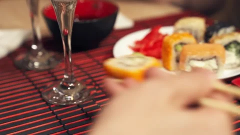 Sushi roll dipped in soy sauce with chopsticks at restaurant table. Stock Footage 345447694