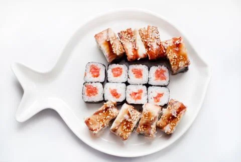 Sushi roll with eel, avocado, cucumber, salmon on a plate in the form of fish Stock Photos