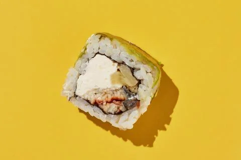 Sushi roll with eel, pineapple, cheese, avocado on yellow. Stock Photos