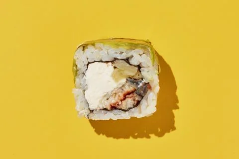 Sushi roll with eel, pineapple, cheese, avocado on yellow. Stock Photos