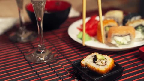 Sushi roll falling apart while picked up with chopsticks in soy sauce. Stock Footage 345447730