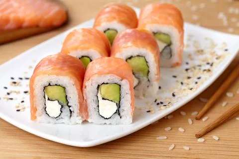 Sushi roll with smoked salmon, avocado, soft cheese and sesame seeds Stock Photos