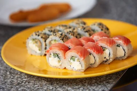 Sushi roll top view on creative orange plate with chopsticks on stone table Stock Photos