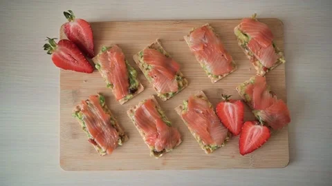 Sushi rolls made with salmon and avocado are arranged on a wooden board Stock Footage 339005062