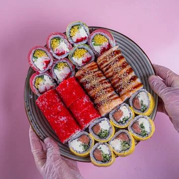 Sushi rolls on a plate presented by hands in a restaurant setting Фото