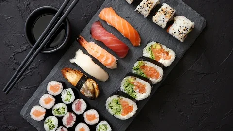 Sushi rolls set with salmon and tuna fish served on black stone board Stock Footage