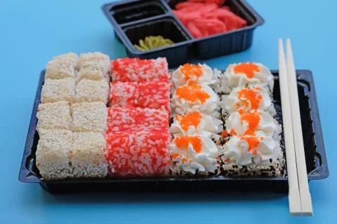 Sushi set in black plastic packaging. Sushi of different types on a blue back Stock-Fotos