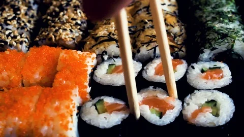 Sushi set on a black table. Chopsticks take sushi close-up. Stock Footage 120996407