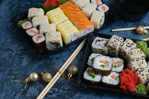 Sushi sets in plastic packaging on a dark background and New Year's decor, fo Fotos Stock