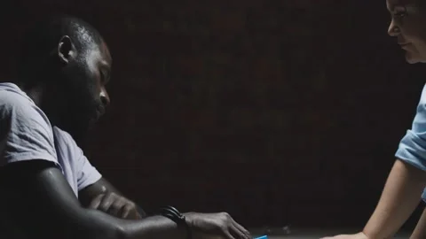Suspect with handcuffs being interviewed in interrogation room by police officer Stock Footage 142808955
