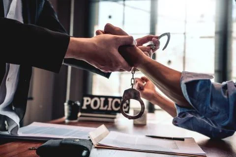 Suspect with handcuffs being interviewed in interrogation room by Police offi Stock Photos