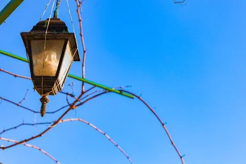 Suspended lantern casting warm light against a serene blue sky on a tranqui.. Stock Photos