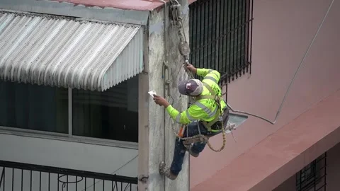 Suspended technician cleans a building facade using safety harness and tools Stock Footage 343882961