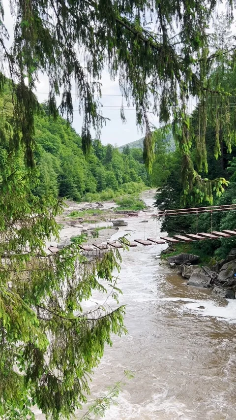 Suspension bridge over a mountain river against the backdrop of mountains.  Stock-Footage 278924309
