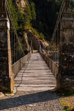 Suspension bridge over a river with a wooden walkway. Stock Photos