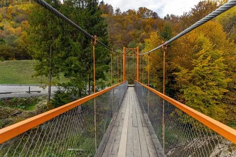 Suspension bridge path through autumn forest. A narrow suspension footbridge Stock Photos