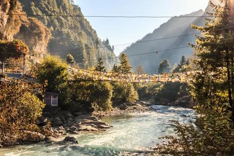 Suspension Bridge with Prayer Flags over River in Nepal Stock Photos