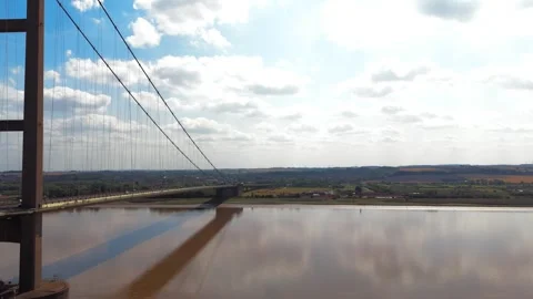 Suspension bridge spans wide river under bright sky Stock-Footage 343546070